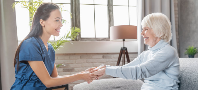 caregiver and elderly holding hands